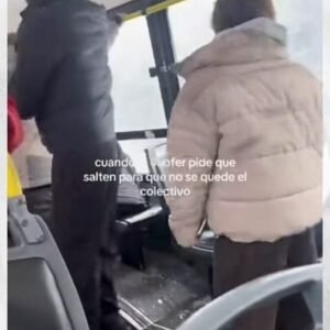 Pasajeros de pie en el fondo de un colectivo, en Bariloche, con nieve visible por la ventanilla