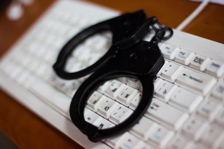 Esposas policiales sobre un teclado de computadora, imagen ilustrativa de cibercrimen