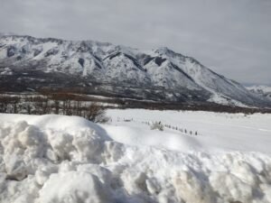 Nieve acumulada al costado de la ruta camino a Bariloche, con la cordillera nevada de fondo. Foto: Paola2022, CC BY-SA 4.0 (Wikimedia Commons)