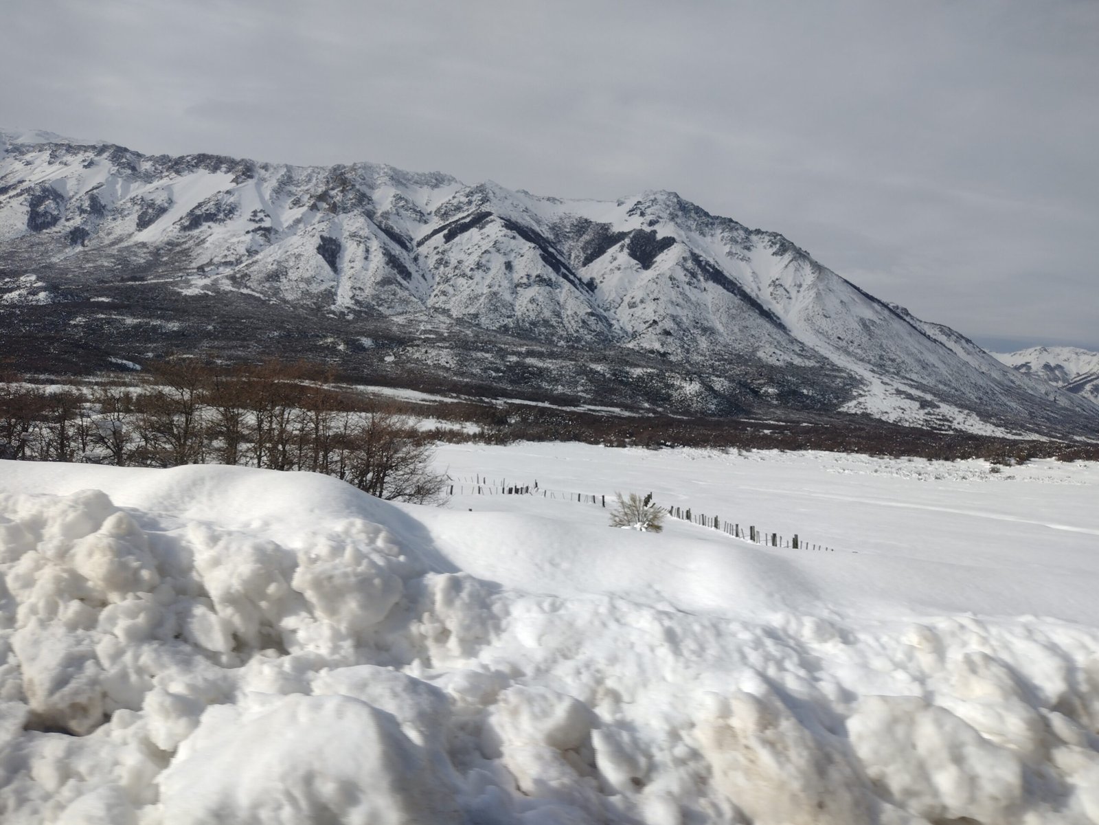 Nieve acumulada al costado de la ruta camino a Bariloche, con la cordillera nevada de fondo. Foto: Paola2022, CC BY-SA 4.0 (Wikimedia Commons)