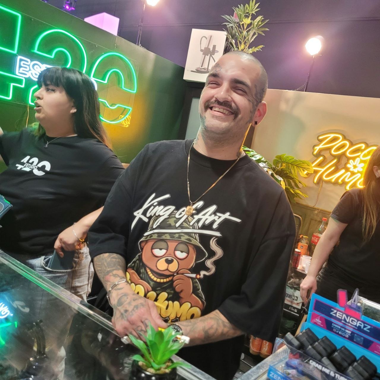 Stand de Estudio 420 en la Expo Cannabis, con una remera de King of Art y el cartel de Poco Humo