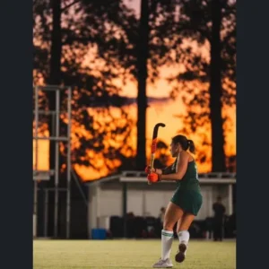 Gisela Arismendi con el palo de hockey durante un partido, al atardecer
